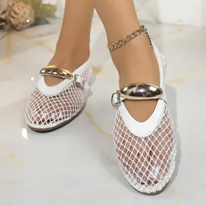 Détail rapproché des sandales plates en maille blanche avec boucle dorée élégante