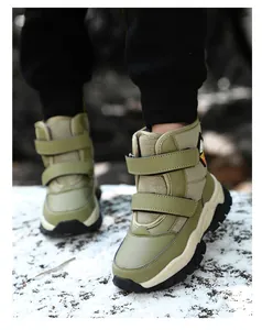 Detail view of durable green children's snow boots with dual velcro straps on snow.