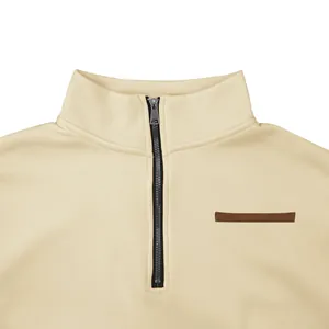 Vue détaillée d'un sweat-shirt beige à demi-zip avec col montant et fermeture éclair.