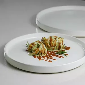 Minimalist white ceramic plate featuring a dessert presentation with caramel sauce