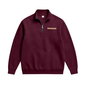 Détail d'un sweat-shirt bordeaux à demi-zip avec col montant et écusson sur la poitrine