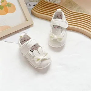 Close-up detail of cute rabbit ear and bow design on white baby canvas walker shoes