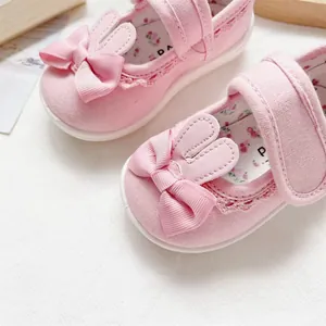 Close-up of pink baby girl canvas walker shoes with cute rabbit ears and bow decoration