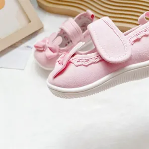 Close-up of pink toddler girl shoes with rabbit bow and delicate lace trim.
