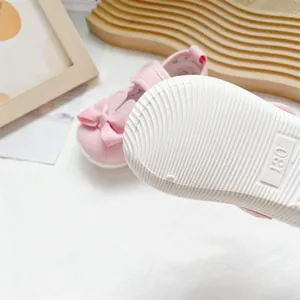 Close-up view of the white non-slip soft sole on pink toddler shoes with bow detail.