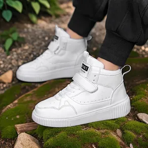 Eleganti sneakers alte bianche da donna con cinturino in velcro su terreno muschiato