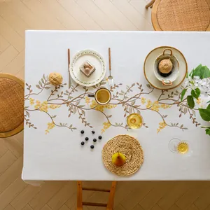Detailed top view of white linen tablecloth featuring elegant yellow floral embroidery