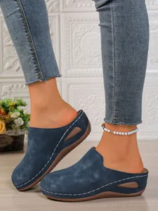 Close-up of women's blue suede closed-toe platform mules with white stitching details