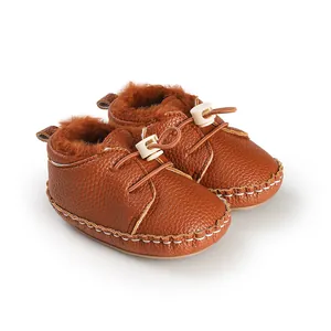 Nahaufnahme von braunen, fleecegefütterten Baby-Lauflernschuhen mit Kordelzug-Verschluss