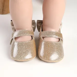 Detailed close-up view of shiny gold glitter baby Mary Jane shoes with back bow detail