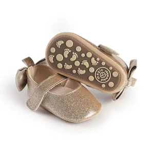 Detail of gold glitter baby girl pre-walker shoes with anti-slip soles and bow.