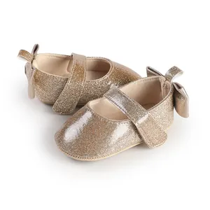 Close-up detailed view of golden glitter baby girl walking shoes with back bow accent