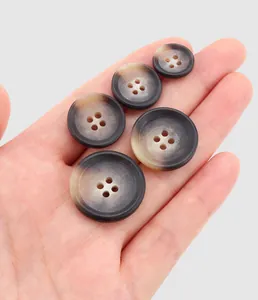 Macro detail of resin buttons with tortoiseshell pattern held in hand for size comparison