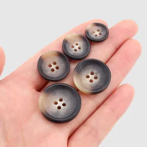 Premium marbled resin buttons in natural brown and tan tones displayed on a palm