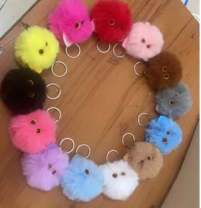 Heart-shaped arrangement of colorful fluffy monster head plush keychains on wood table.