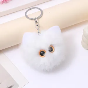 Close-up detail of a fluffy white plush cat head keychain with realistic orange eyes