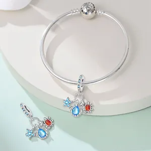 Close-up of silver-plated ocean theme charms with blue and orange cubic zirconia stones