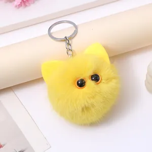 Detailed close-up of a bright yellow plush cat head keychain with soft fur and cute big eyes