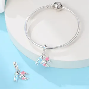 Close-up of silver travel airplane and ticket charms with pink flowers for bracelet
