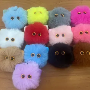 Collection of colorful plush cat head keychains with cute eyes on a wooden table