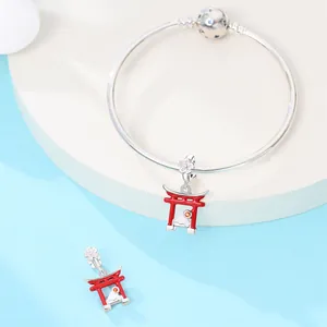 Detailed macro view of a silver snake chain bracelet with red Torii gate and cherry blossom charms