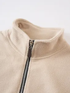 Close-up detail of stand collar and smooth zipper on a thick beige fleece jacket