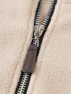 Detail of premium metal zipper with leather puller on thick beige fleece jacket