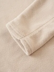 Macro view showing the high-quality soft beige fleece fabric and durable cuff stitching.