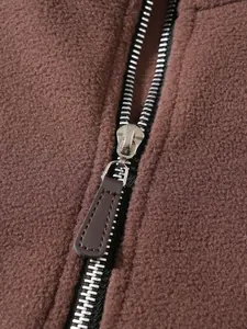 Close-up macro detail of high-quality metal zipper on textured brown fleece sweatshirt jacket