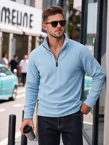 Detail view of a man wearing a light blue half-zip fleece sweatshirt in an urban setting