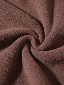 Macro detail shot showing the soft texture of the brown polar fleece fabric for a sweatshirt
