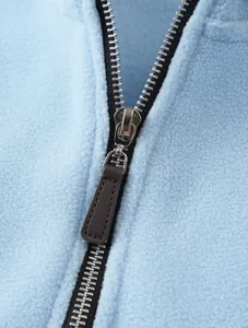 Detailed view of the silver metal zipper and brown leather pull on blue fleece sweater
