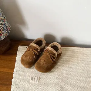 Detailed view of brown suede children's moccasins with warm fleece lining and decorative bow