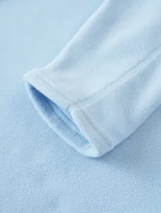 Macro view of thick polar fleece texture and cuff detail on light blue men's zip sweatshirt