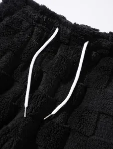 Detailansicht von schwarzem Fleece mit Karomuster und weißen Kordelzug-Bändern.