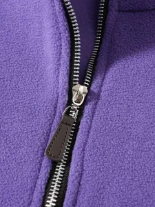 Detailed macro shot of silver metal zipper with brown leather pull on purple fleece jacket