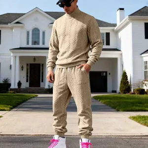Full body view of a man wearing a stylish beige cable-knit sweater and joggers tracksuit