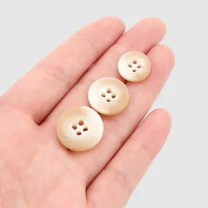 Premium pearlized round resin buttons for clothing shown in three sizes on palm