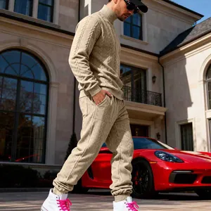 Model wearing khaki cable knit high-neck sweater and joggers in luxury setting.