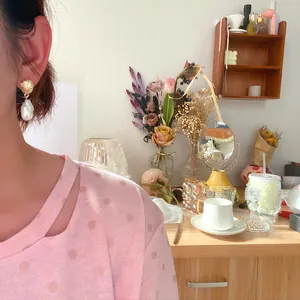 Eleganti orecchini in perle barocche irregolari con borchie dorate indossati da modella