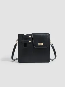 Front view of a minimalist black crossbody bag with gold hardware and twist lock
