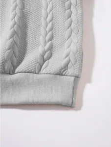 Detailed view of light gray cable knit and quilted fabric on a men's sweatshirt hem