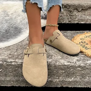 Primo piano dei sabot in camoscio beige con suola in sughero e fibbia regolabile