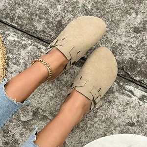 Primo piano di eleganti sabot in camoscio beige indossati con jeans su pietra