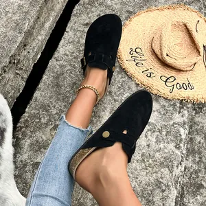 Primo piano di sabot in pelle scamosciata nera con suola in sughero e pantaloni denim