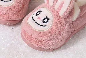 Macro view of pink plush toddler boots with cute cartoon bunny face embroidery.