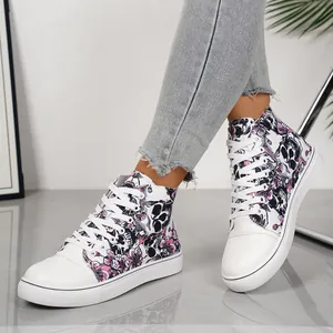 Close-up van hoge canvas sneakers met een stijlvol printpatroon van schedels en roze bloemen.