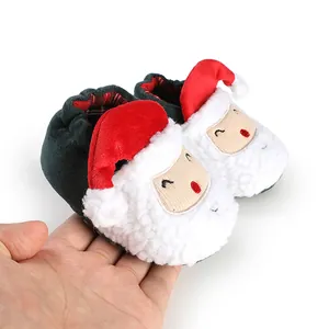 Detailed macro view of plush Santa Claus baby shoes being held to show texture and size.