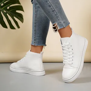 Detailopname van witte hoge canvas sneakers gedragen door een model in blauwe spijkerbroek