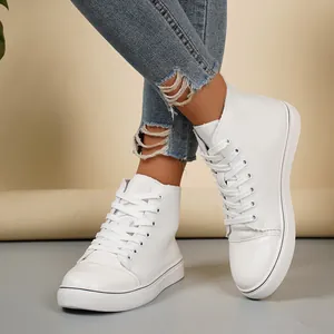 Close-up van witte hoge canvas sneakers gedragen met distressed blauwe spijkerbroek